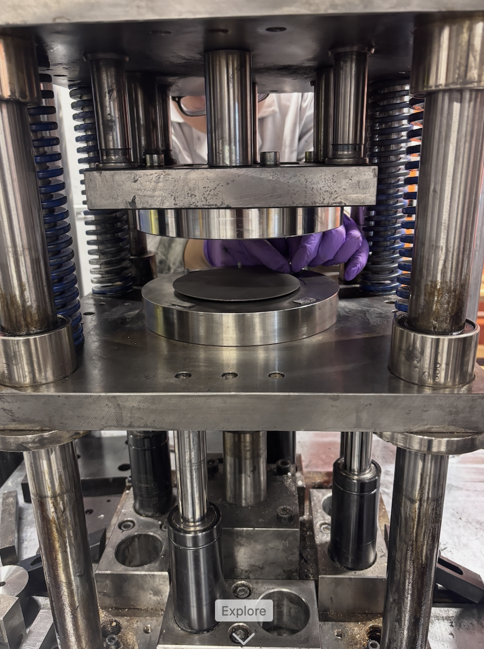 100-tonne hydraulic press rig with a circular titanium blank between the dies
